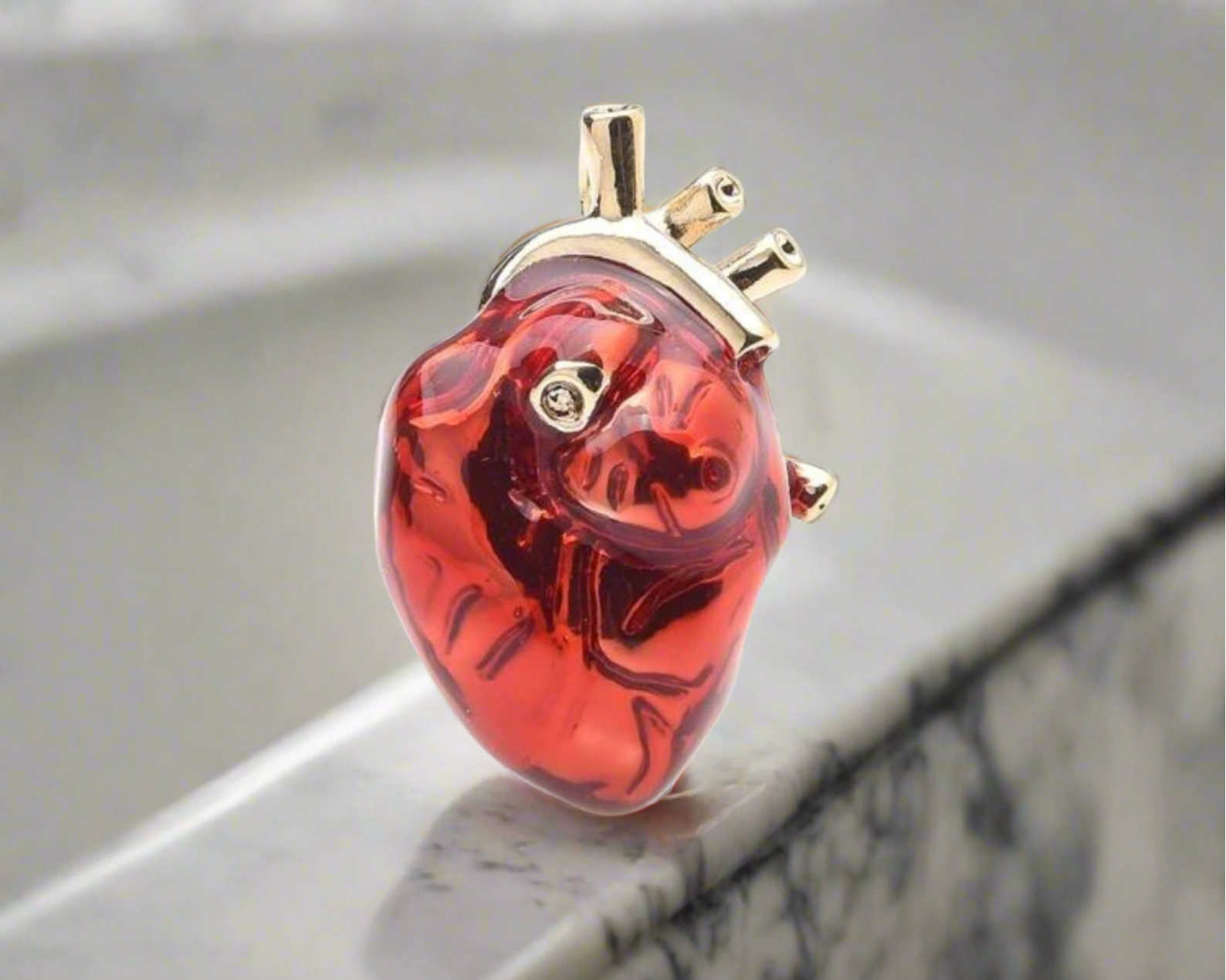 Close-up of the red and gold heart pin against a black suit, emphasizing its bold statement.