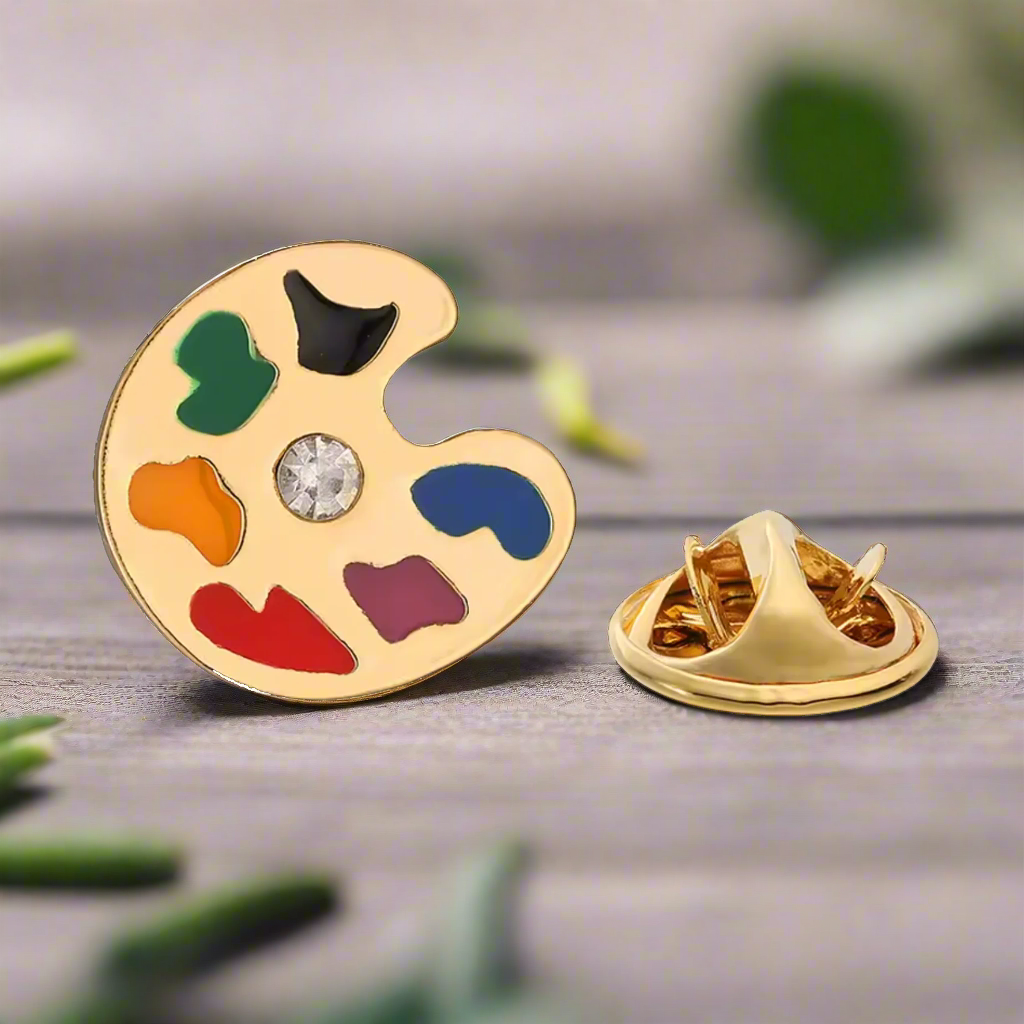 Close-up of a colorful artist palette lapel pin on a blazer, showcasing vibrant paint dabs