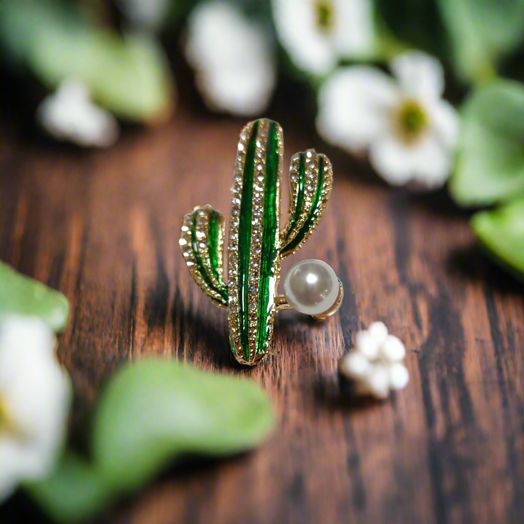 Close-up of the green enamel cactus pin against a light tan shirt, showcasing its intricate details.