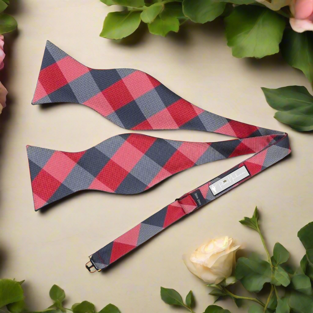 Man adjusting a vibrant plaid self-tie bow tie with a classic suit for a formal event