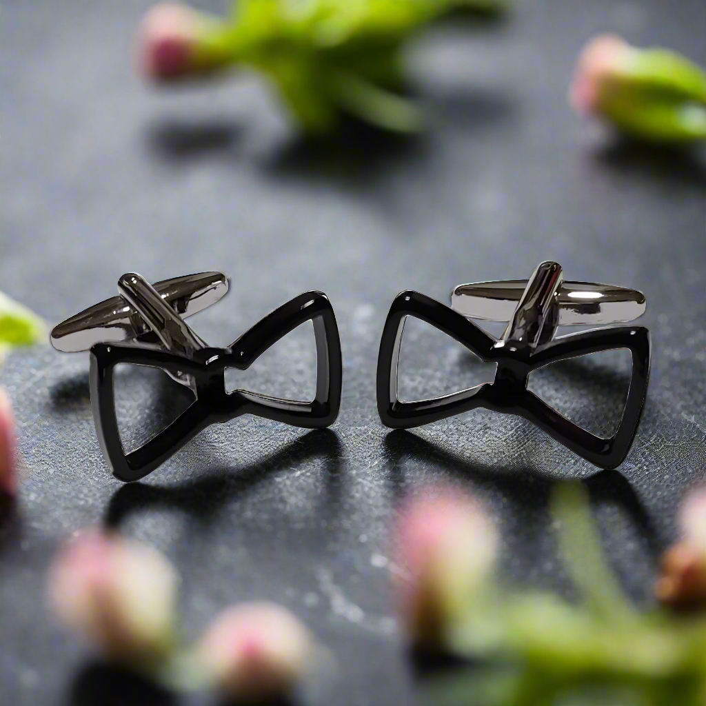 Elegant chrome and black bow tie cufflinks on a white shirt cuff