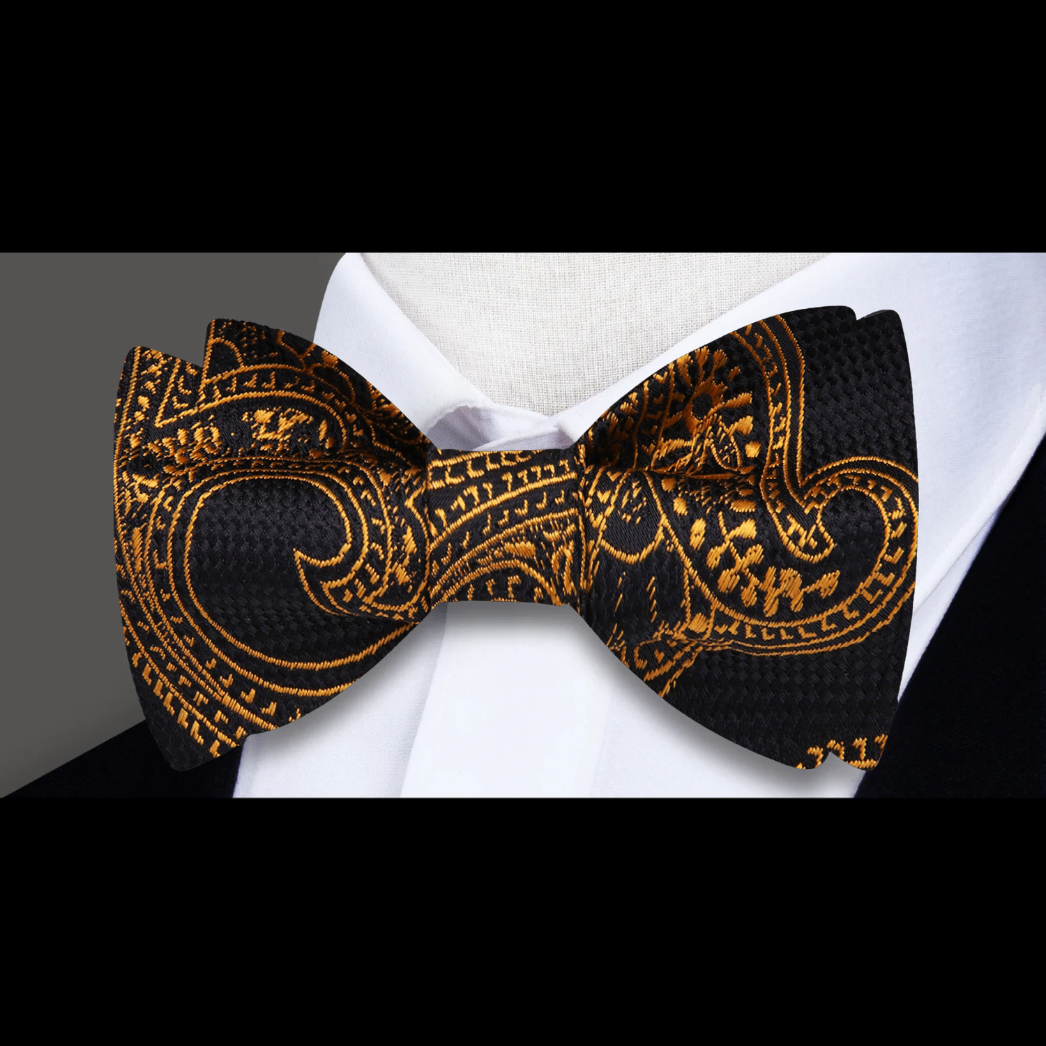 Close-up of the luxurious black and antique gold paisley bow tie, showcasing its intricate design and silk texture.