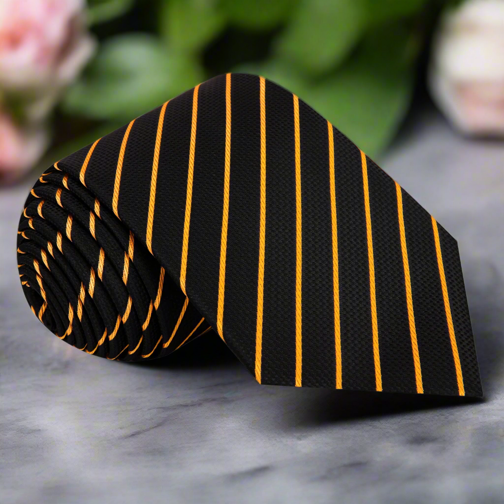 Close-up of black silk tie with gold stripes laying on a charcoal suit