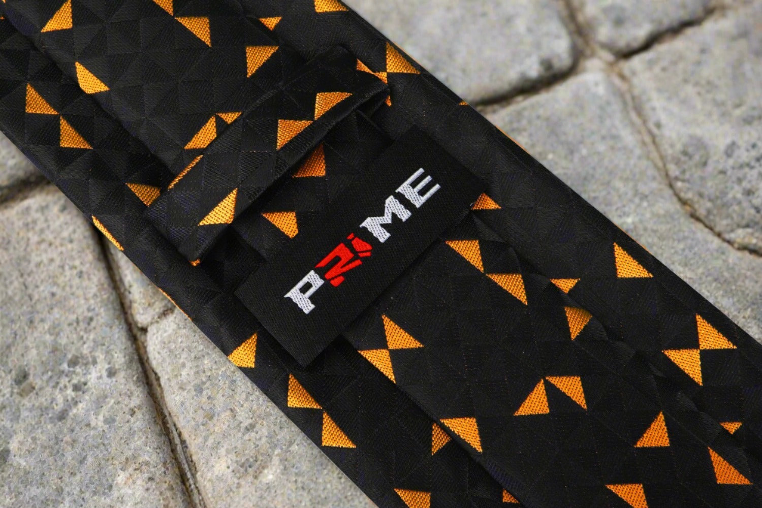 Elegant black silk tie with orange triangle design paired with a white dress shirt