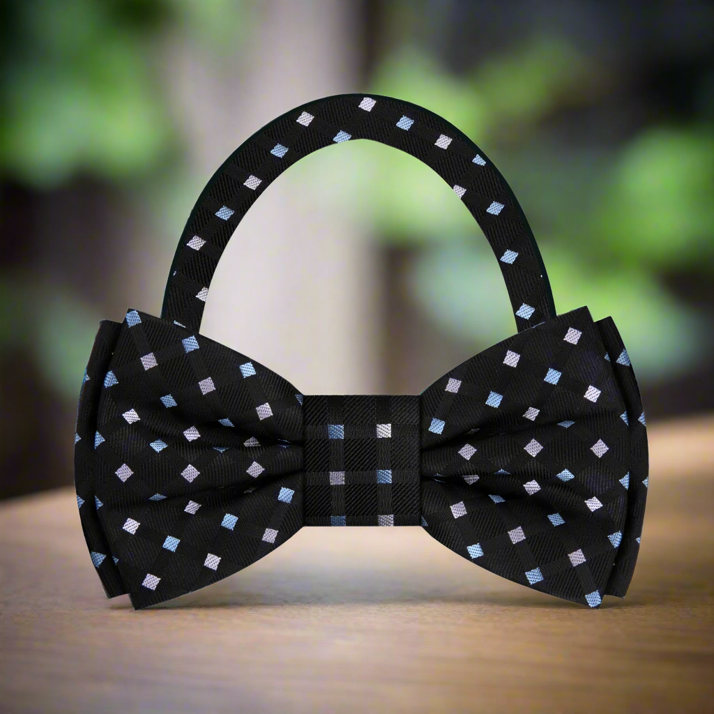 Elegant black silk bow tie with pink and purple geometric pattern, showcased on a mannequin.