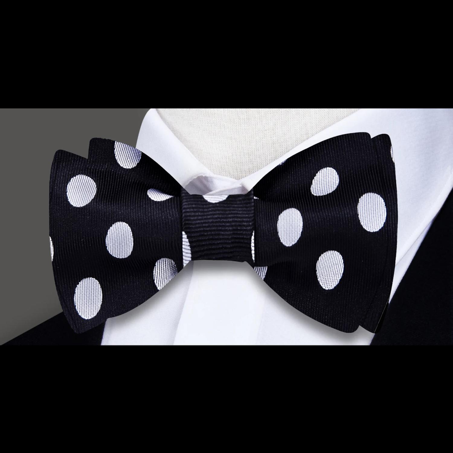 Front view of a black polka dot bow tie styled with a white dress shirt