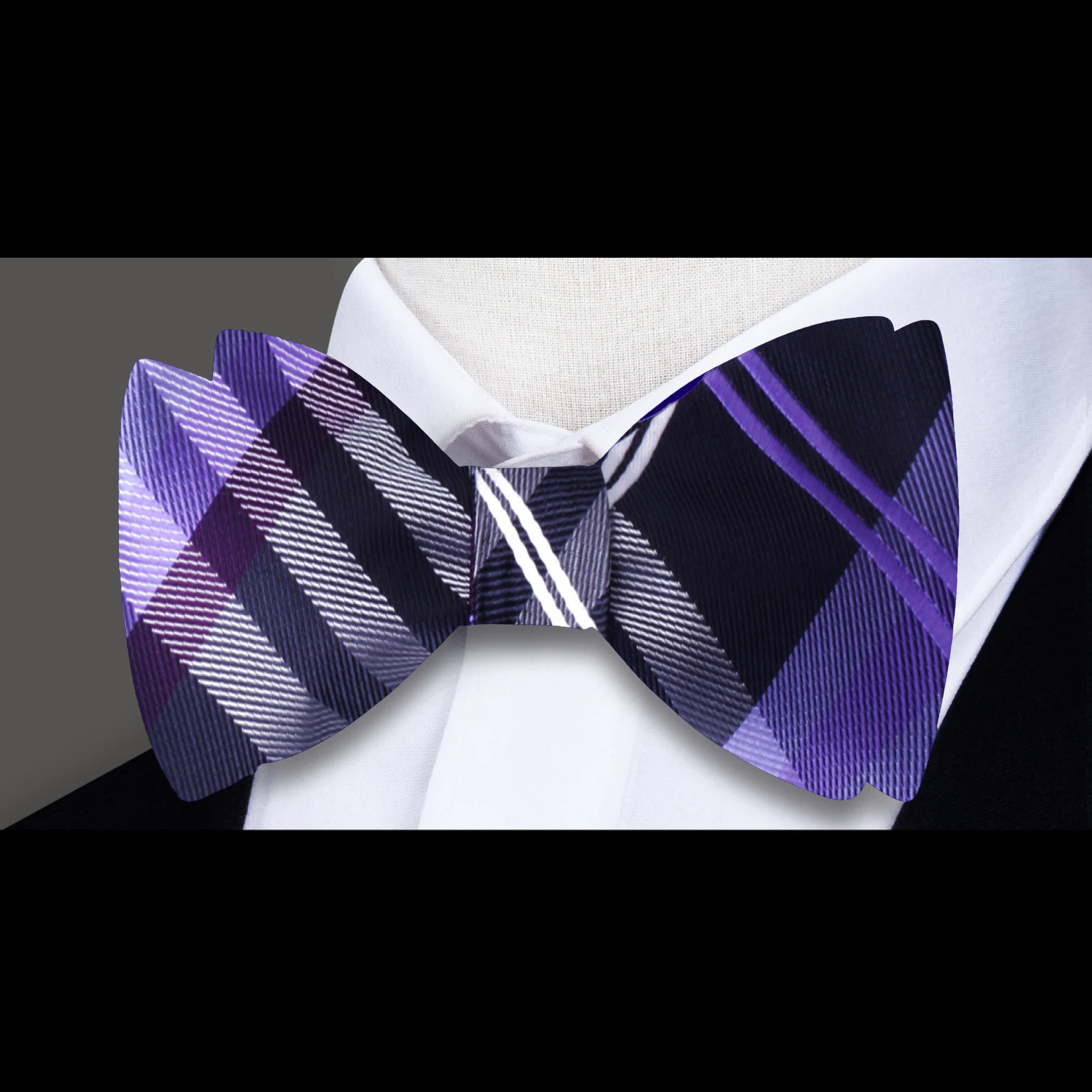 Men tying a plaid bow tie in a modern office setting