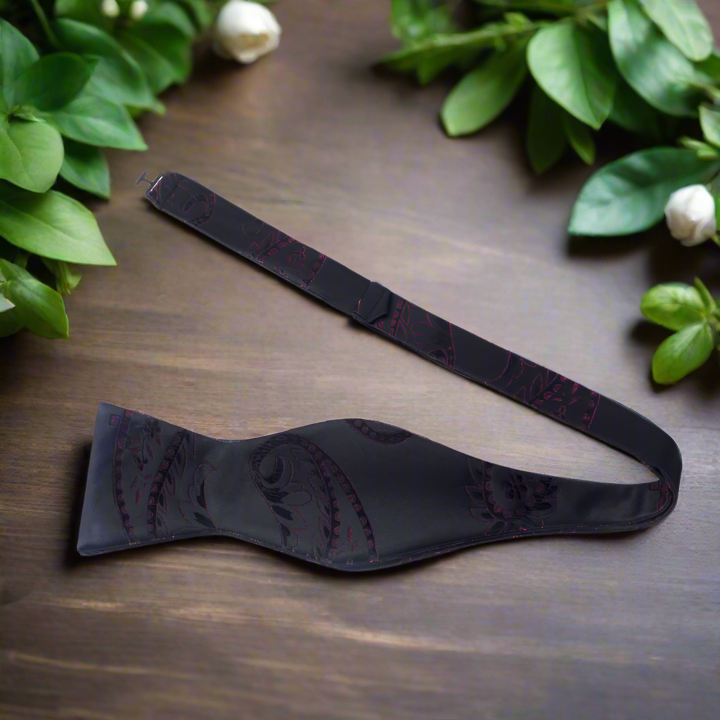Elegant red and black paisley silk bow tie worn with formal suit for wedding