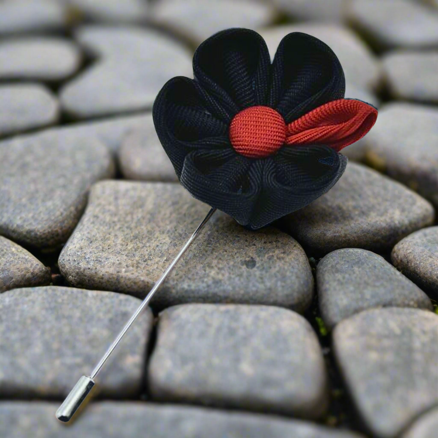 Close-up of elegant black and red handcrafted lapel pin, showcasing intricate details and fine craftsmanship.