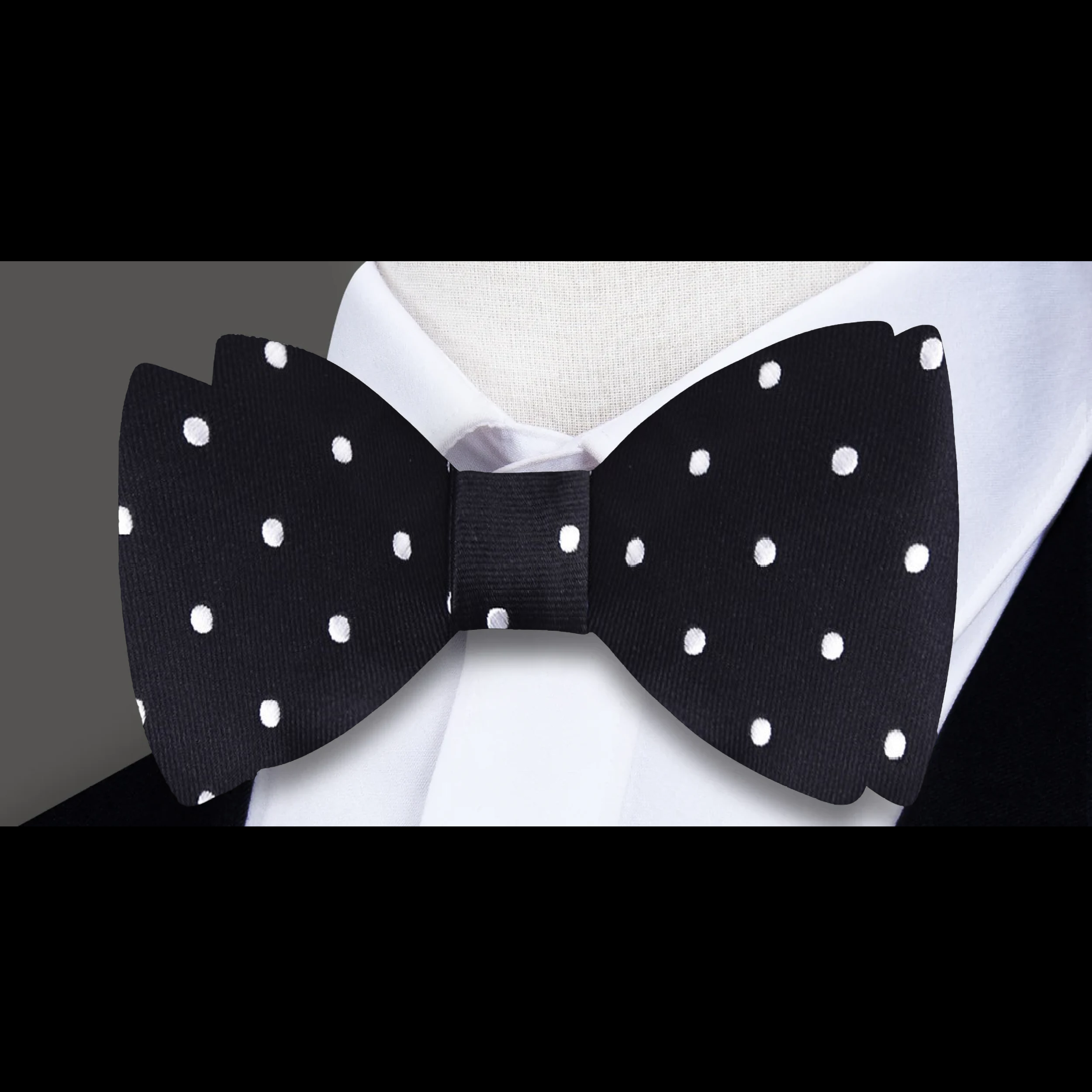 Front view of black silk pre-tied bow tie with white polka dots, styled for formal events