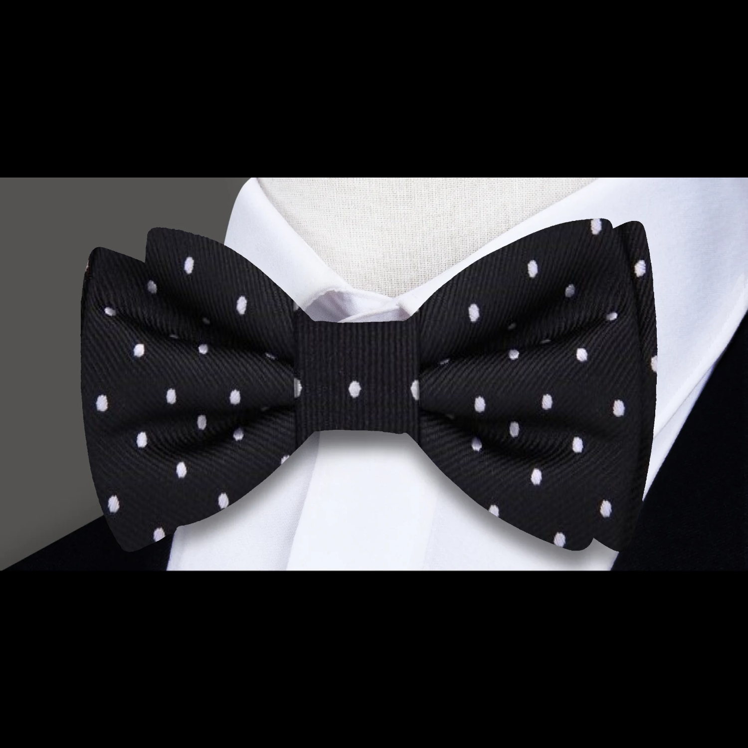 Close-up of the silk bow tie, highlighting the small white dots against the black fabric.