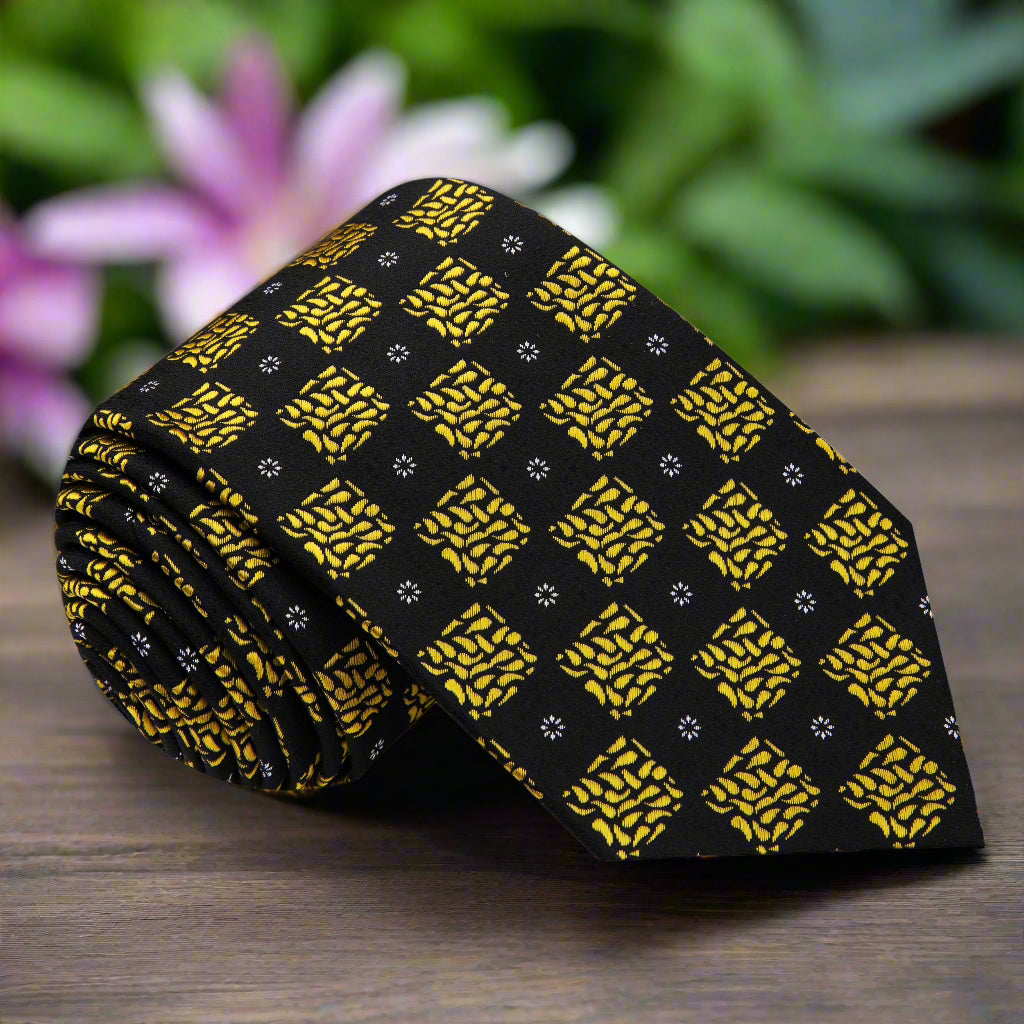 Close-up of black and gold geometric necktie showcasing bold pattern and luxurious silk fabric