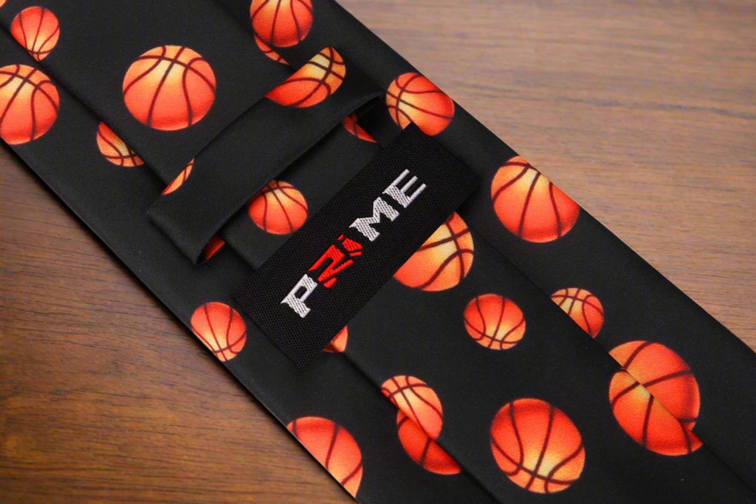 Close-up of orange basketballs woven into the black silk necktie.