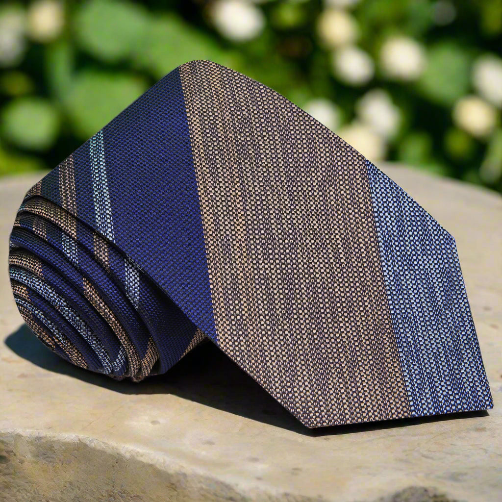 Front view of striped tie showcasing silk texture and blend of grey, blue, and brown tones.
