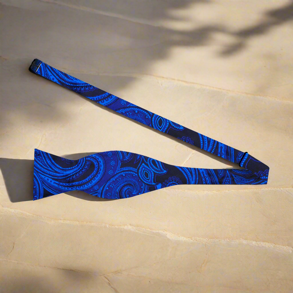 Close-up of the vibrant paisley pattern on a black and blue self-tie bow tie.