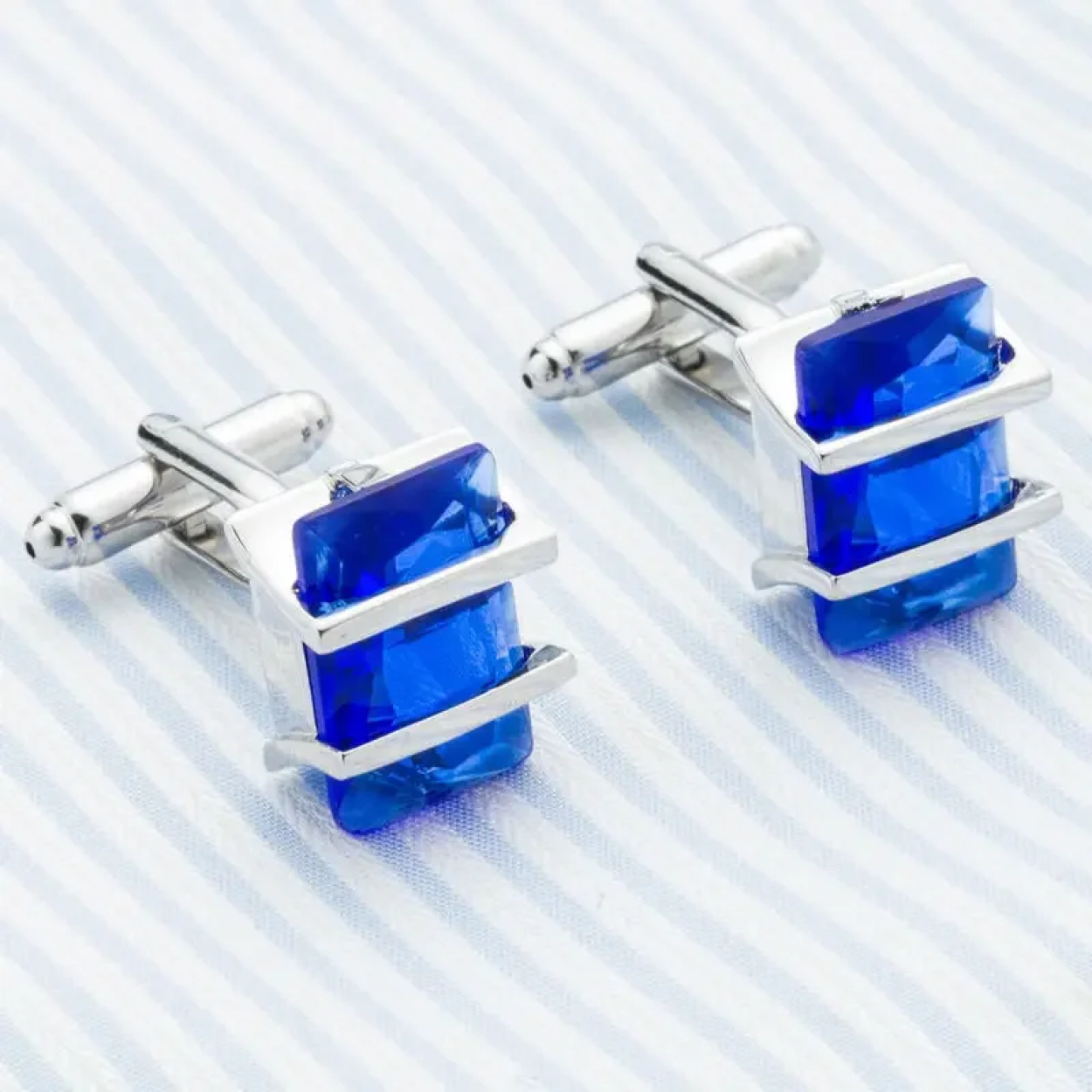 Flat lay of chrome greenstone cufflinks surrounded by a tailored suit, perfect for formal occasions.