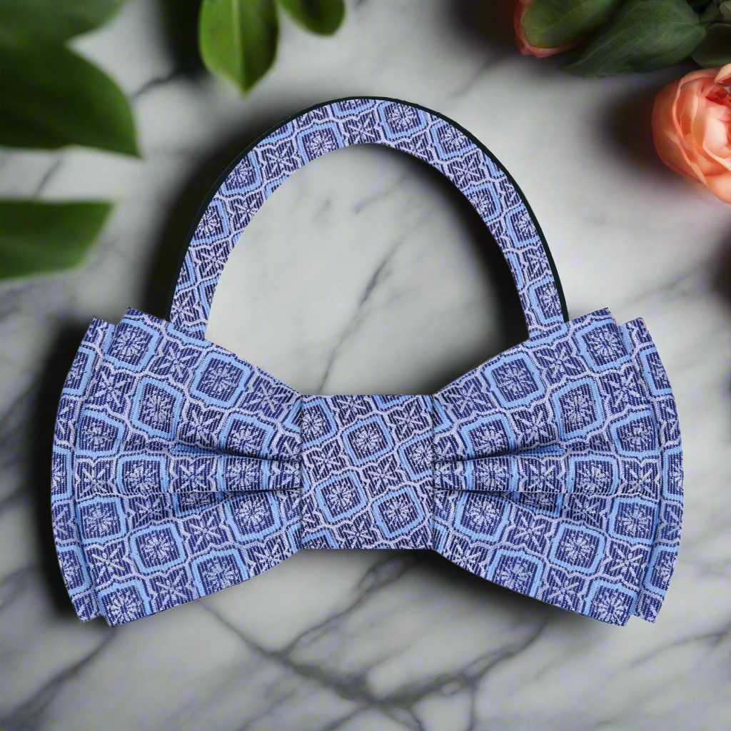 Flat lay of the vibrant geometric silk bow tie alongside a charcoal grey suit and a pocket square.