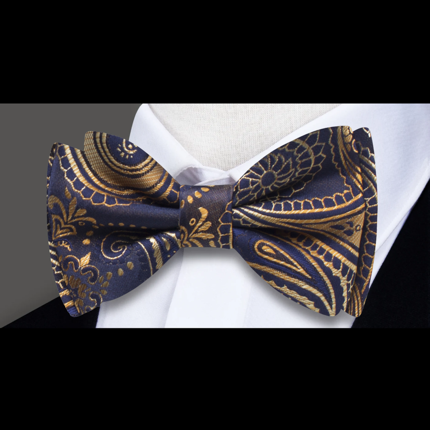 Close-up of dark blue and antique gold paisley pattern on a silk bow tie