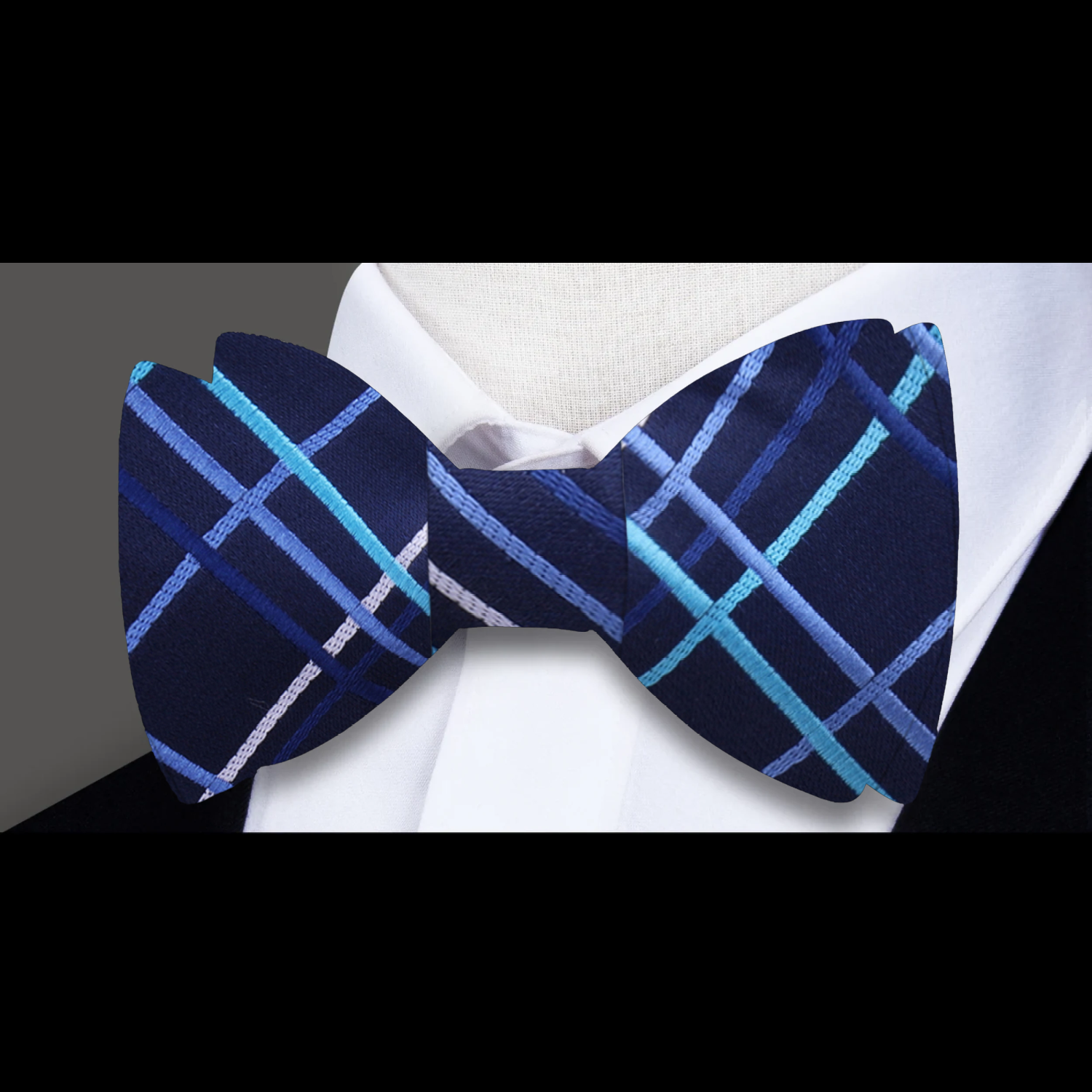 Dark blue bow tie paired with a light blue dress shirt and navy suit for a formal look.