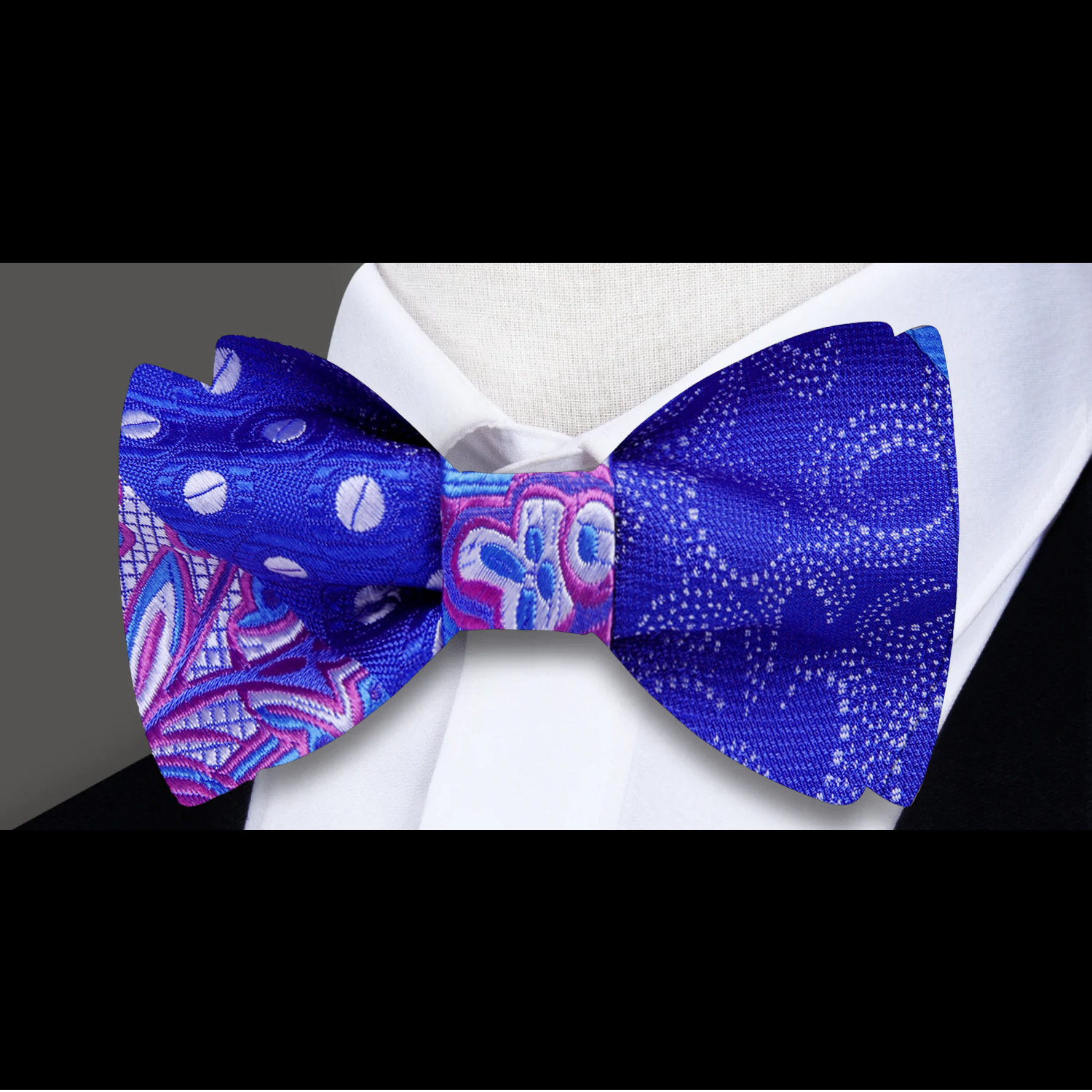 Elegant blue, purple, and white silk bow tie laid out for display, showcasing intricate paisley and polka dot designs.