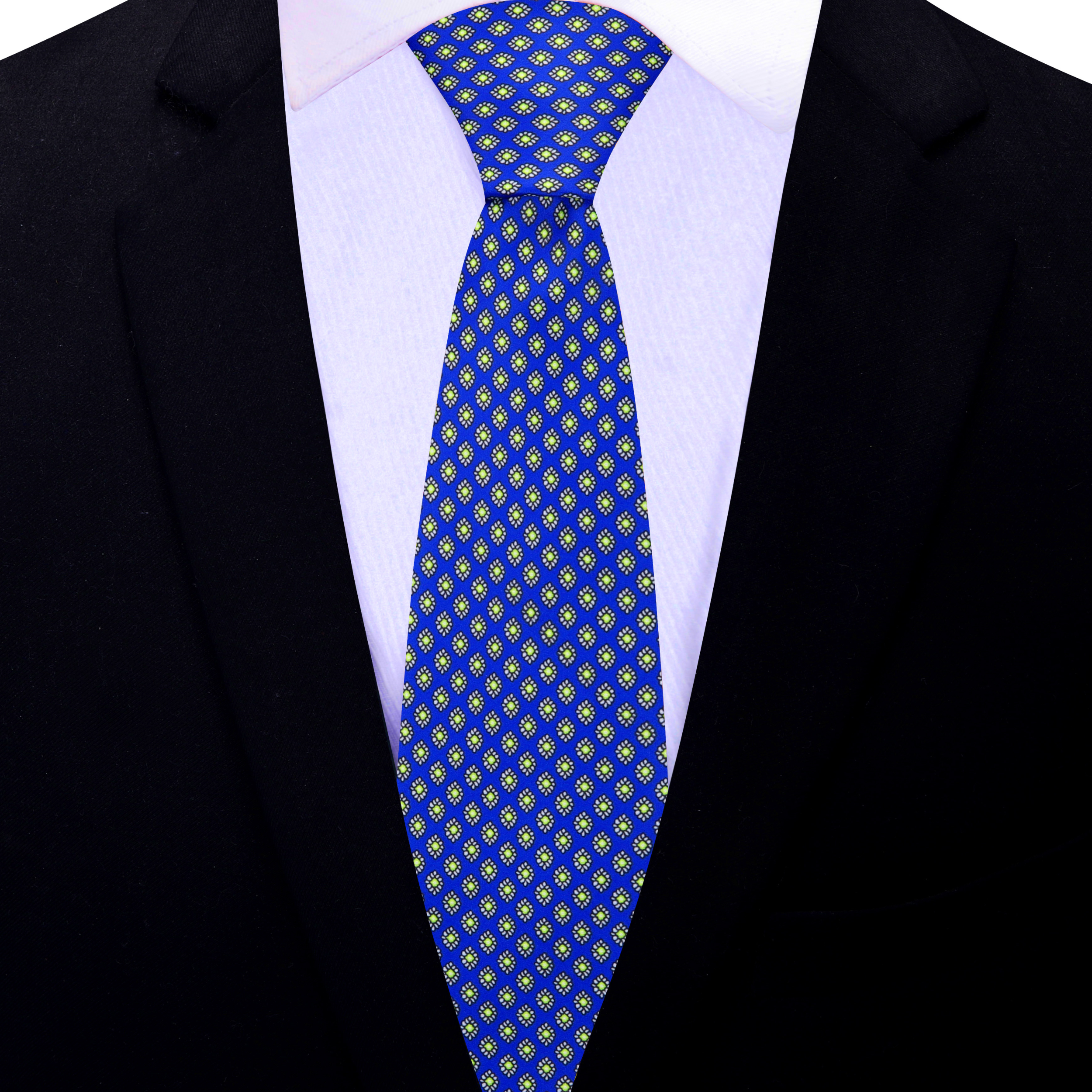 Top-down view of blue silk necktie with green medallion pattern on a white shirt.