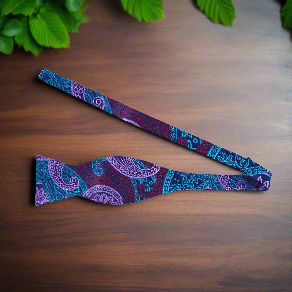 Man adjusting a self-tie paisley bow tie with vibrant pattern