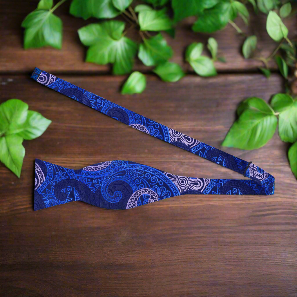 Man adjusting a self-tie paisley bow tie with vibrant pattern