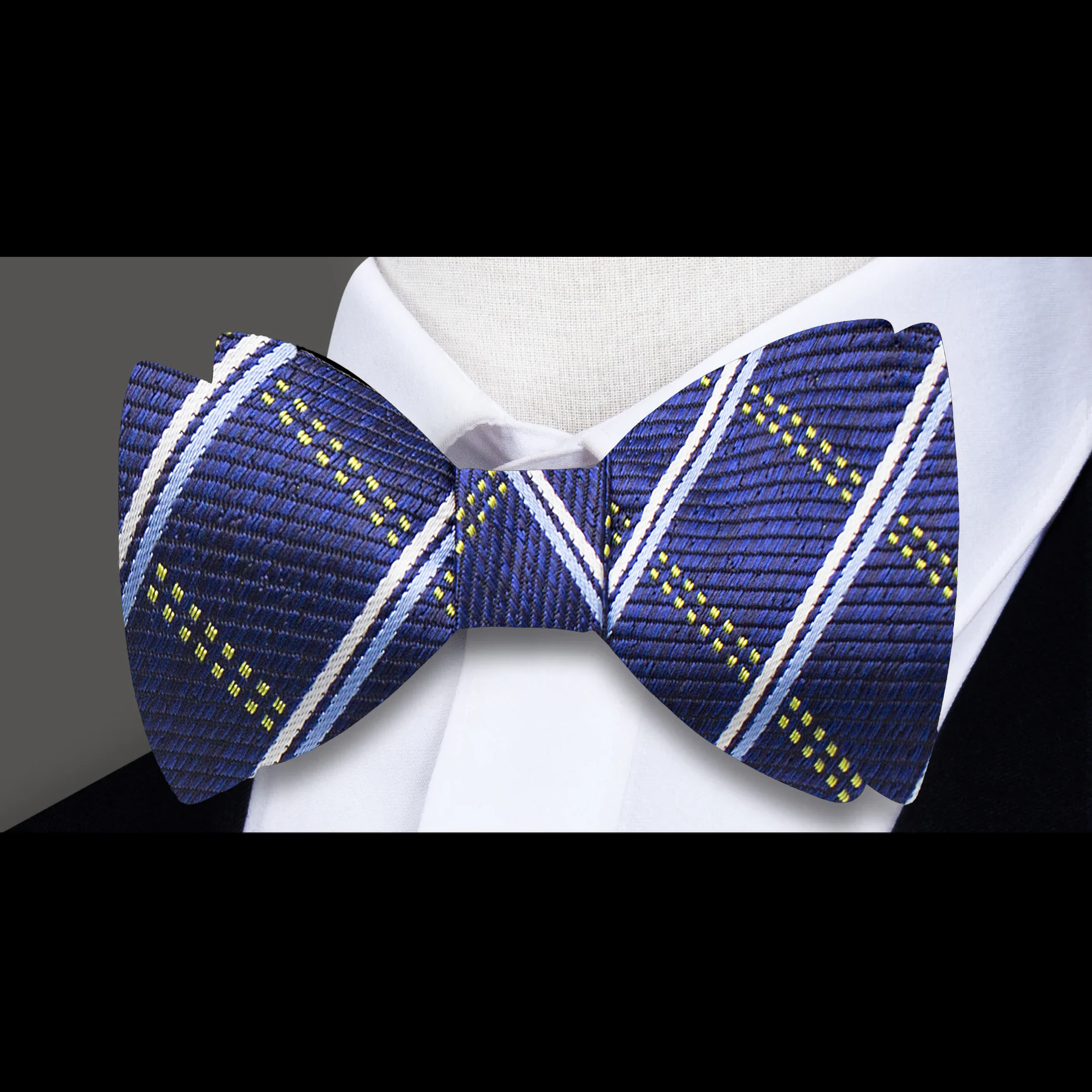 Close-up of the intricate plaid design of the silk bow tie against a light background.