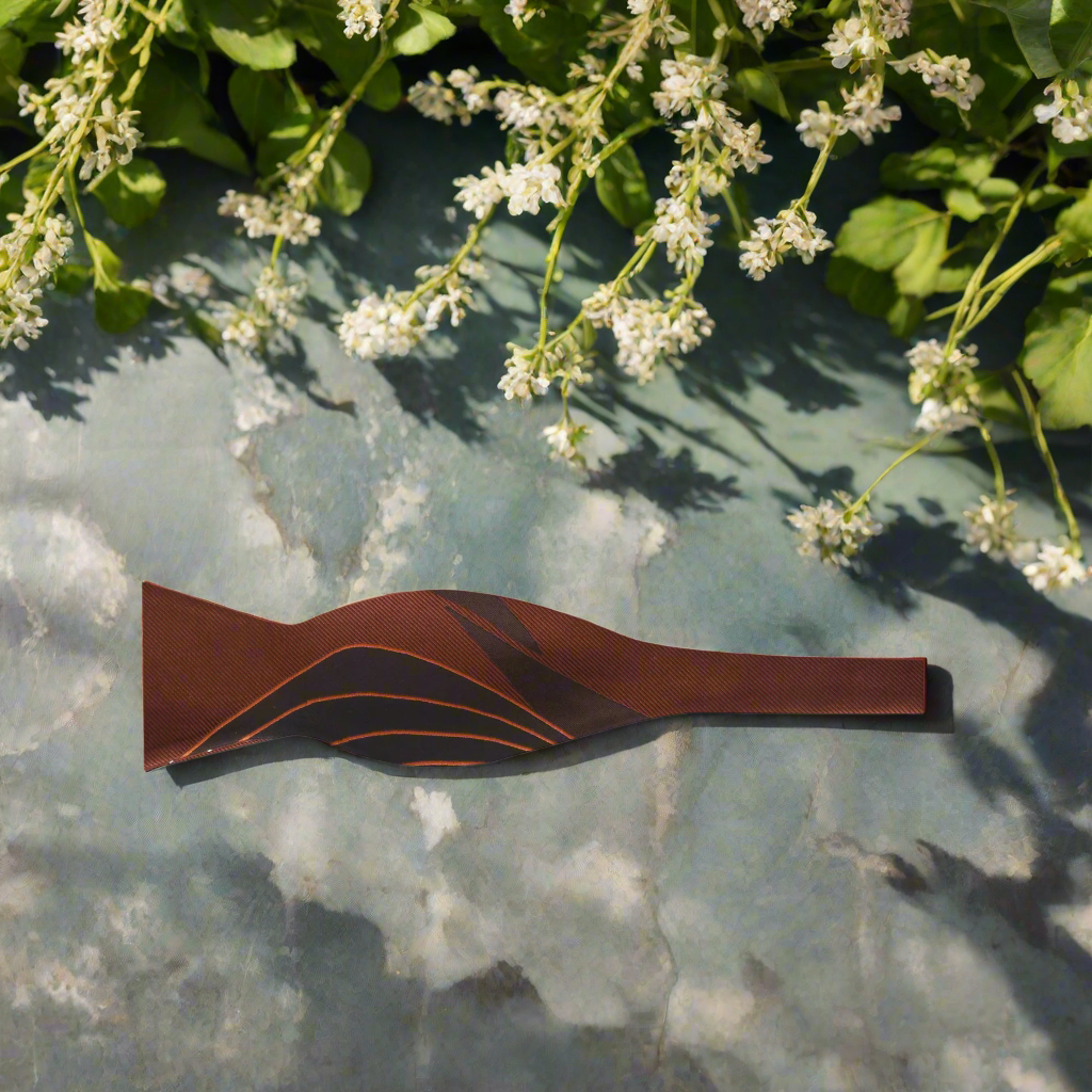 Close-up of the elegant brown abstract silk bow tie, highlighting the rich textures and colors.