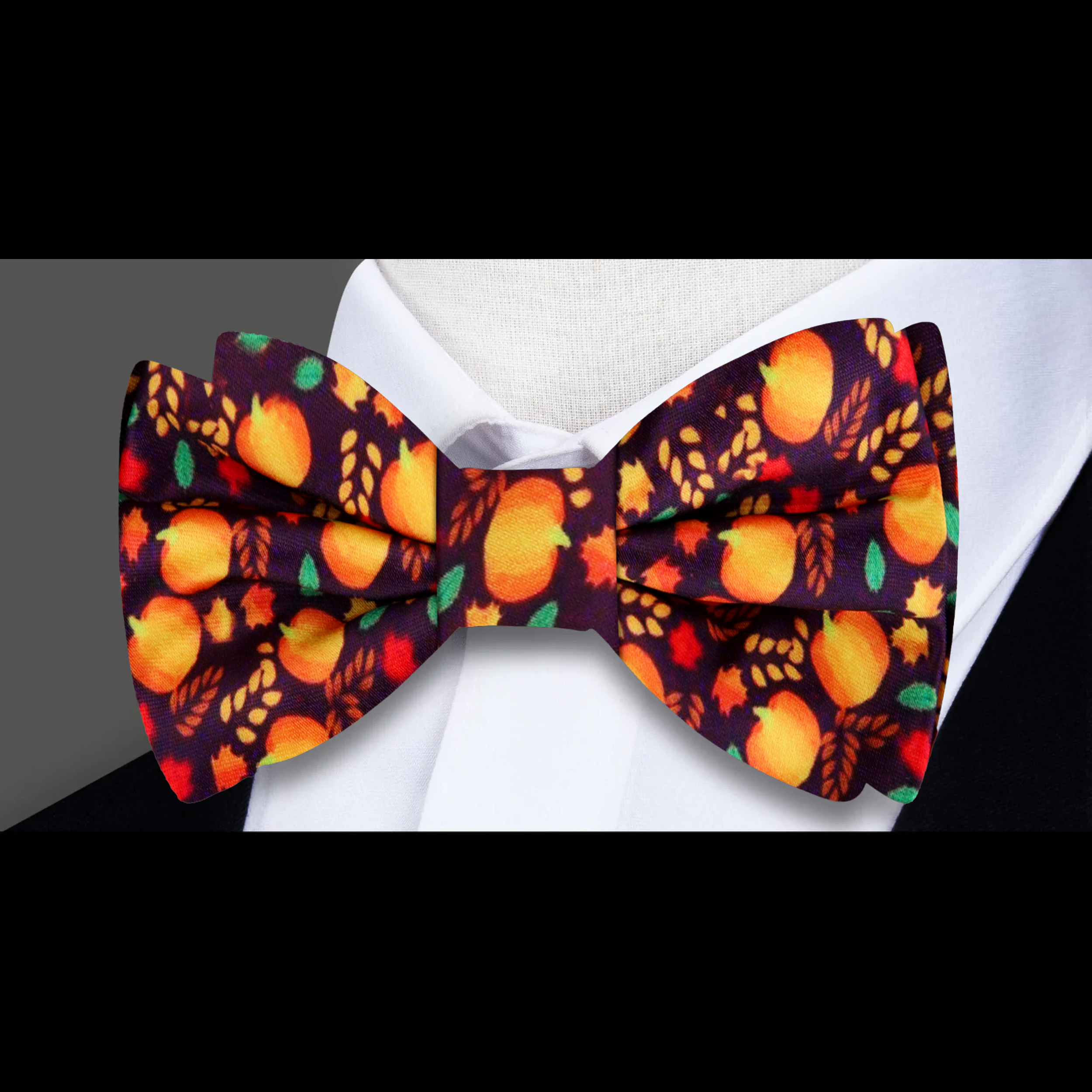 Man wearing fall leaves and pumpkin silk bow tie outdoors in fall foliage