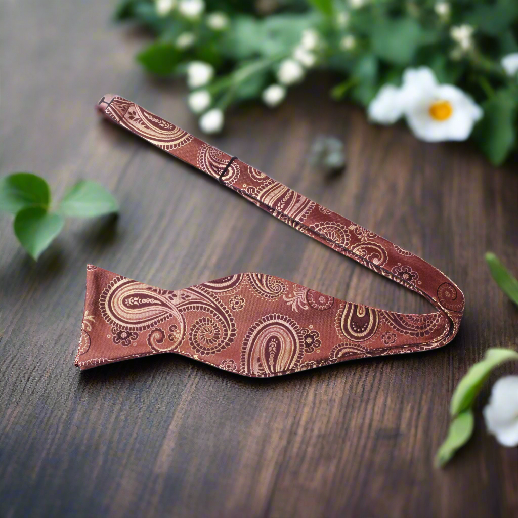 Elegant brown and gold paisley silk bow tie worn with a tuxedo for evening wear