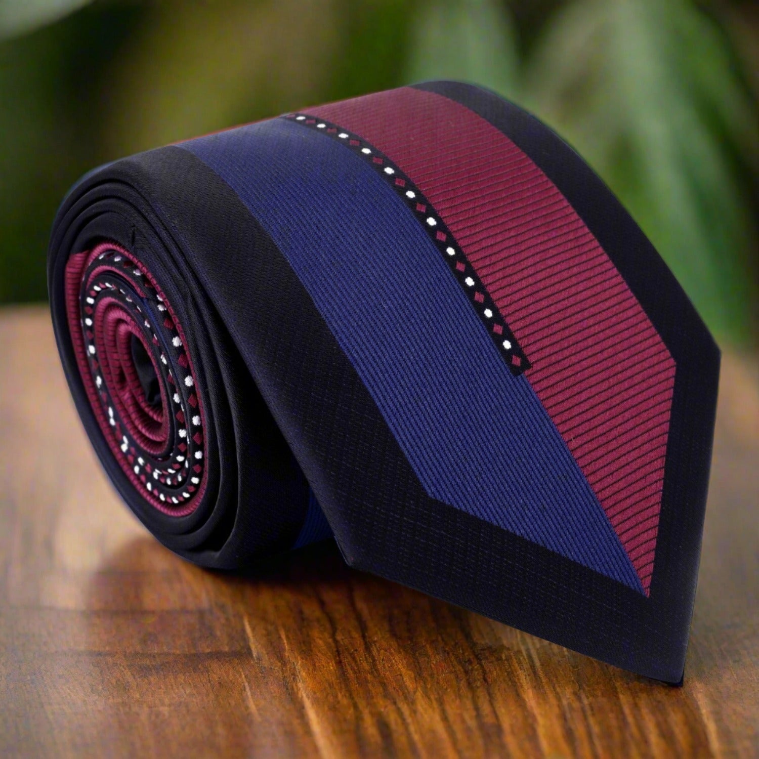 Burgundy and dark blue silk tie displayed on a wooden table, showcasing its luxurious fabric and elegant design.