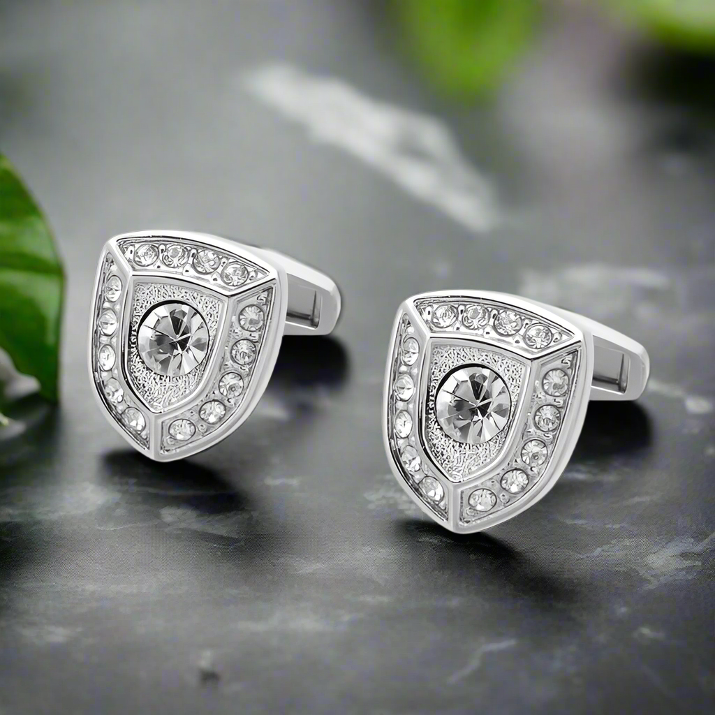Close-up of gold shield cufflinks with stones, detailed design