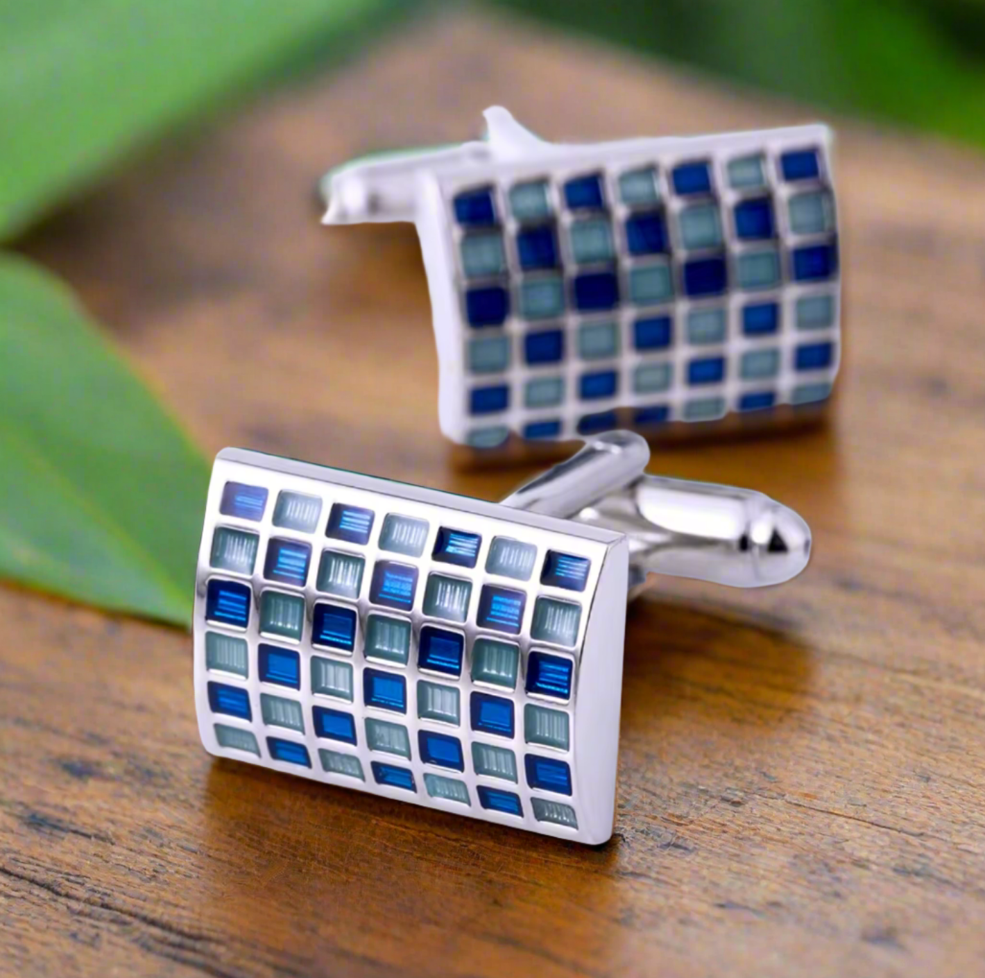 Elegant blue check cufflinks displayed on a soft fabric background, highlighting their unique rectangular shape and check texture.