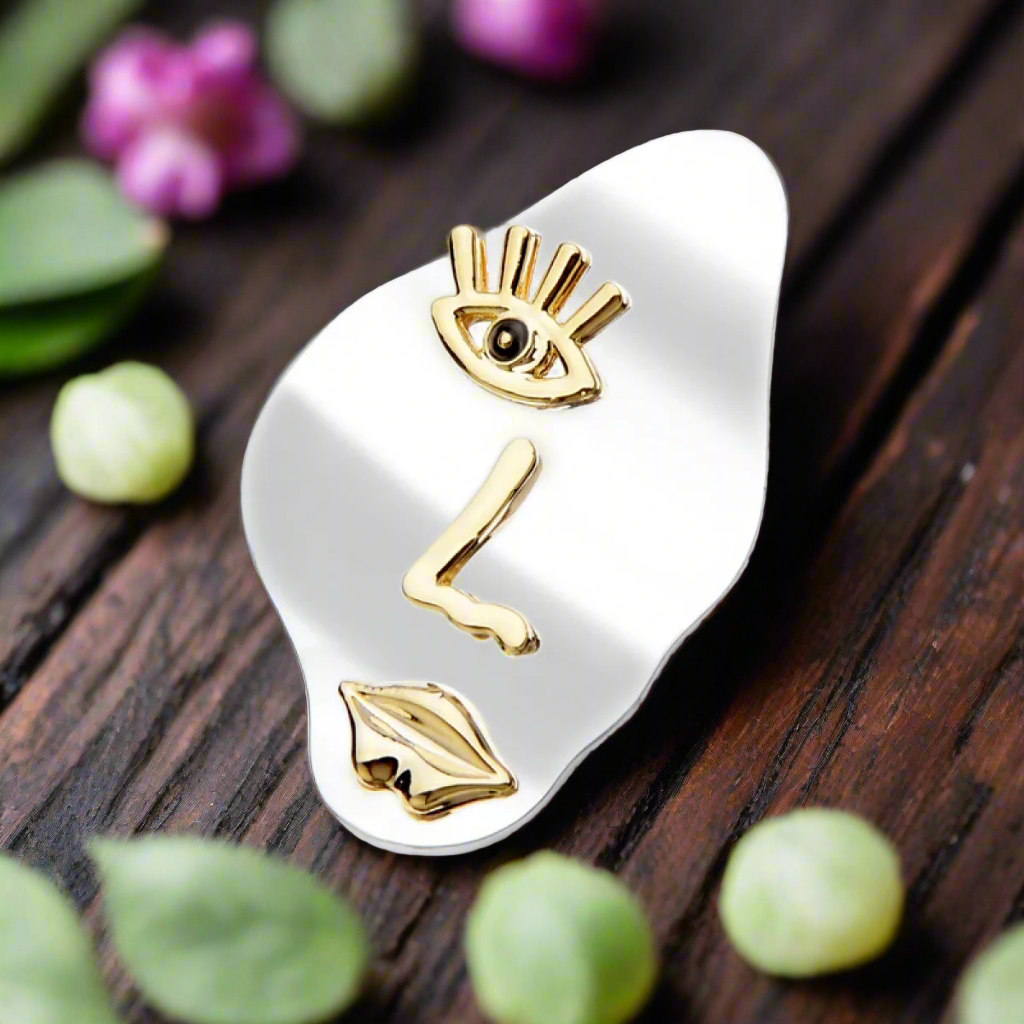The unique face design brooch positioned on a dark blazer, highlighting its versatility for formal occasions.