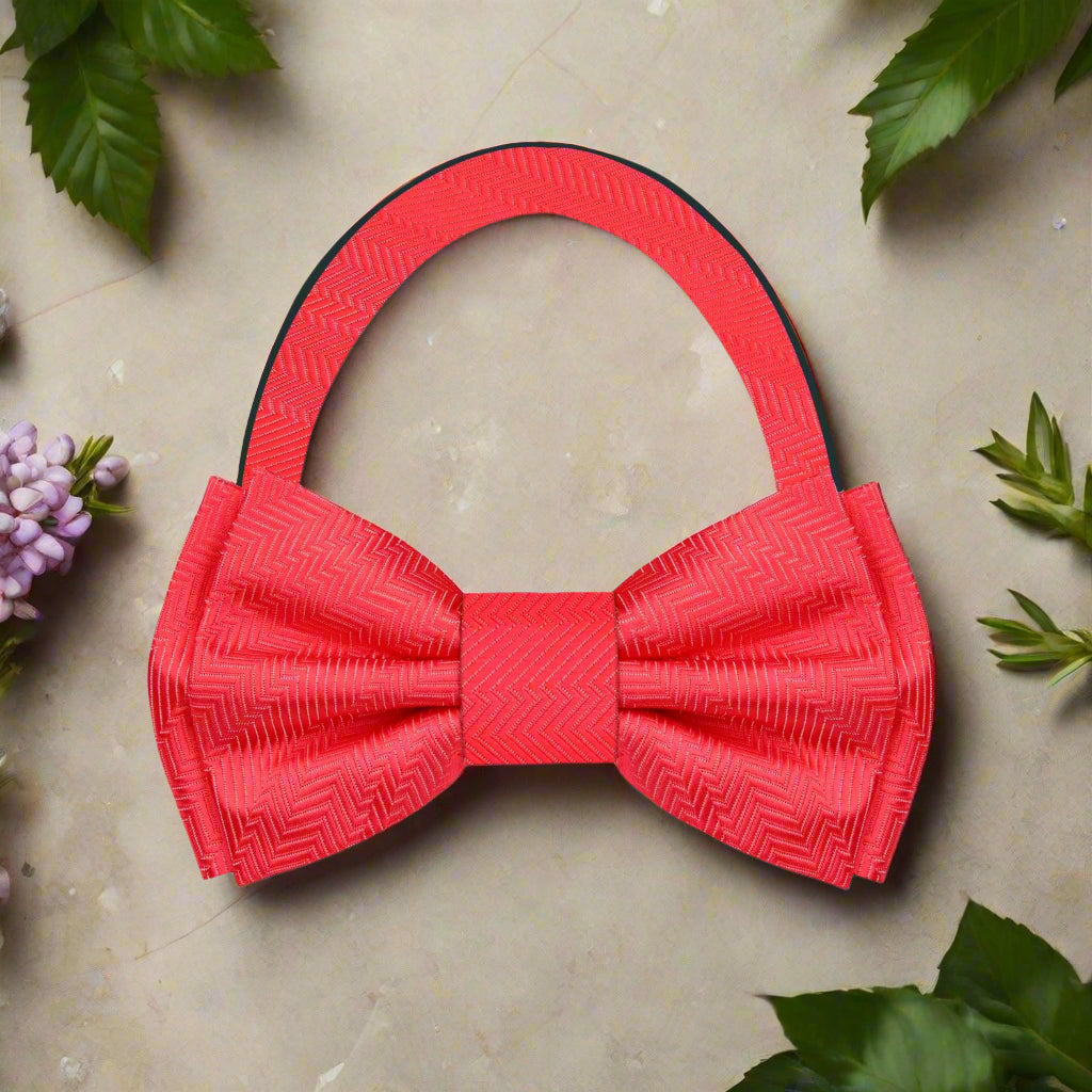 Stylish garnet red silk bow tie paired with a matching pocket square on a navy blue suit jacket, ideal for weddings.