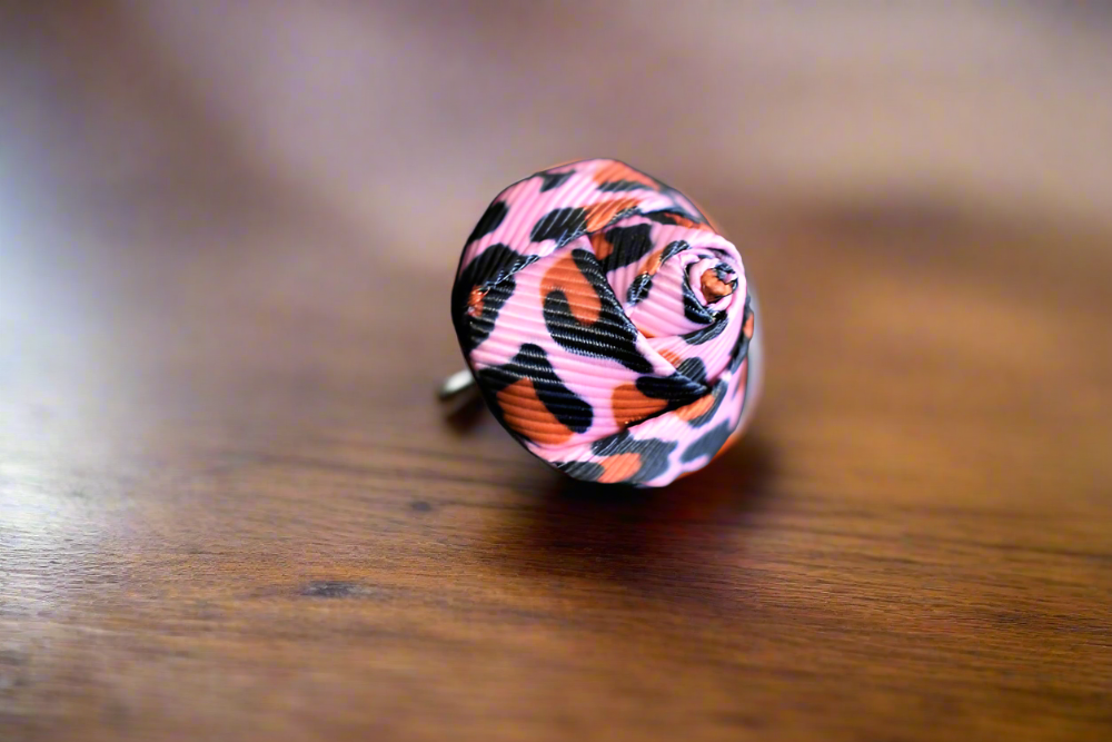 Vivid pink rose bud lapel pin on a dark suit lapel, showcasing elegant design