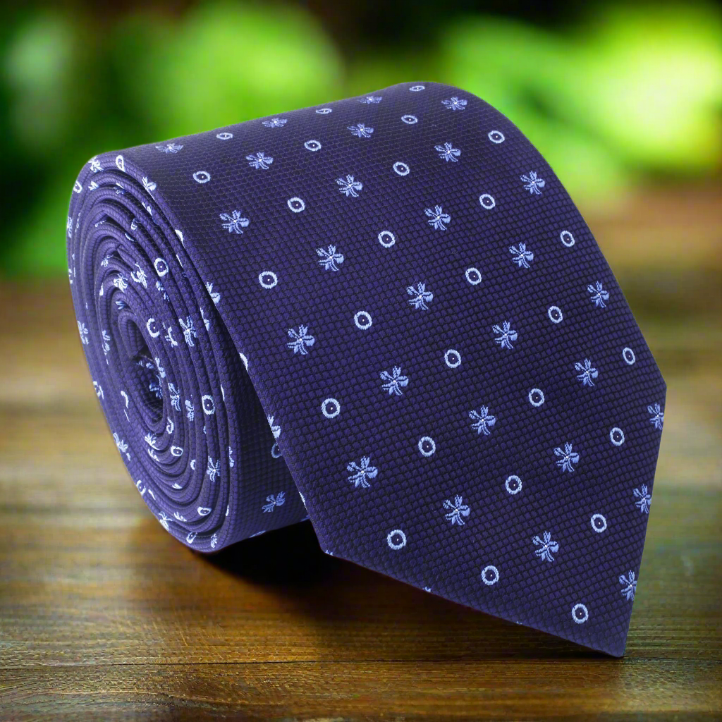 Dark blue silk tie with geometric pattern displayed on a wooden surface.