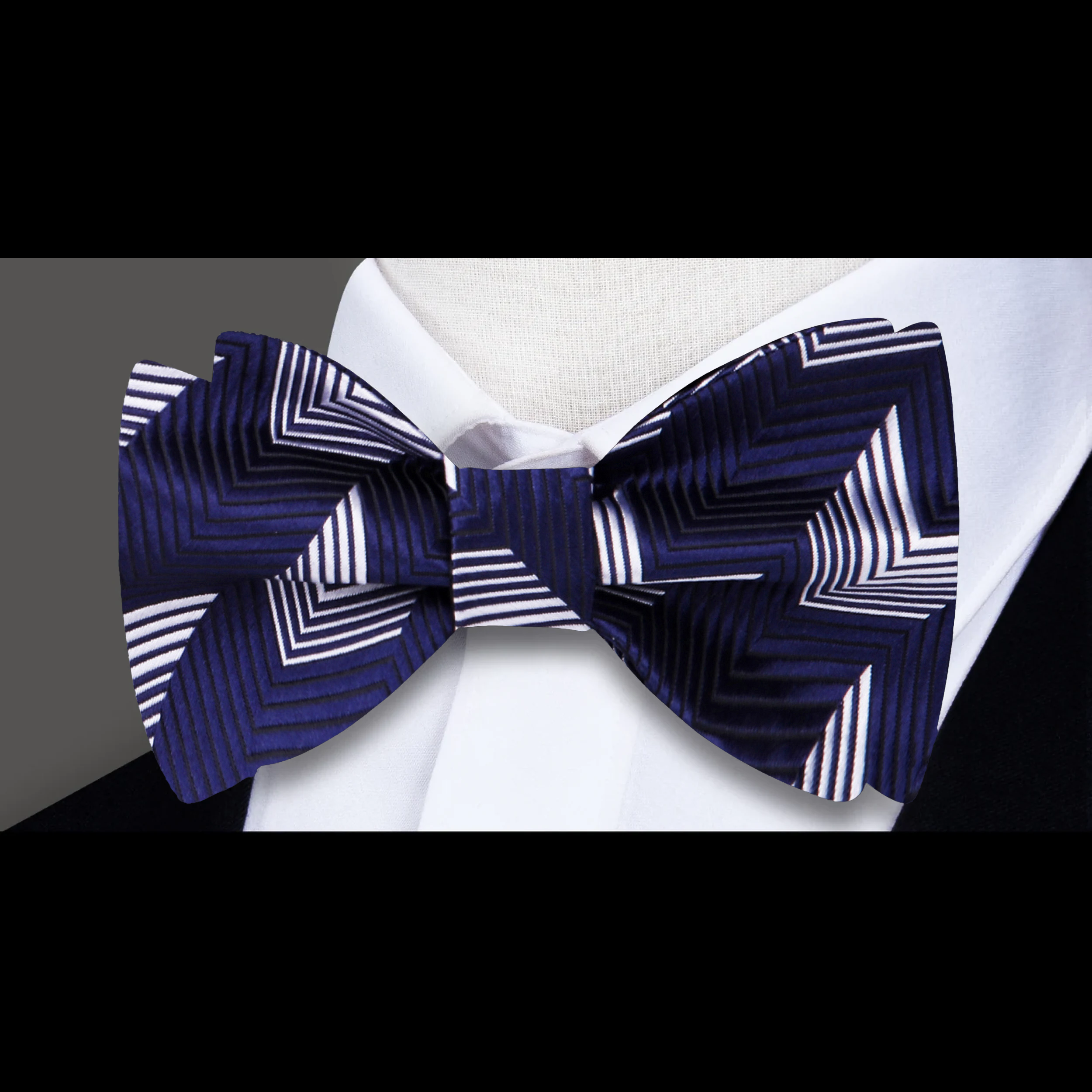 Styled image of a man wearing a red chevron bow tie with silver accents at a wedding