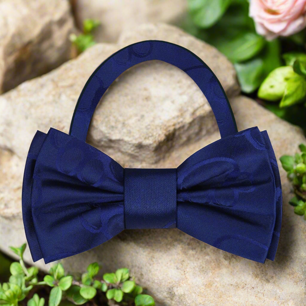 Close-up of the paw print pattern on a dark blue bow tie, showcasing its unique design.