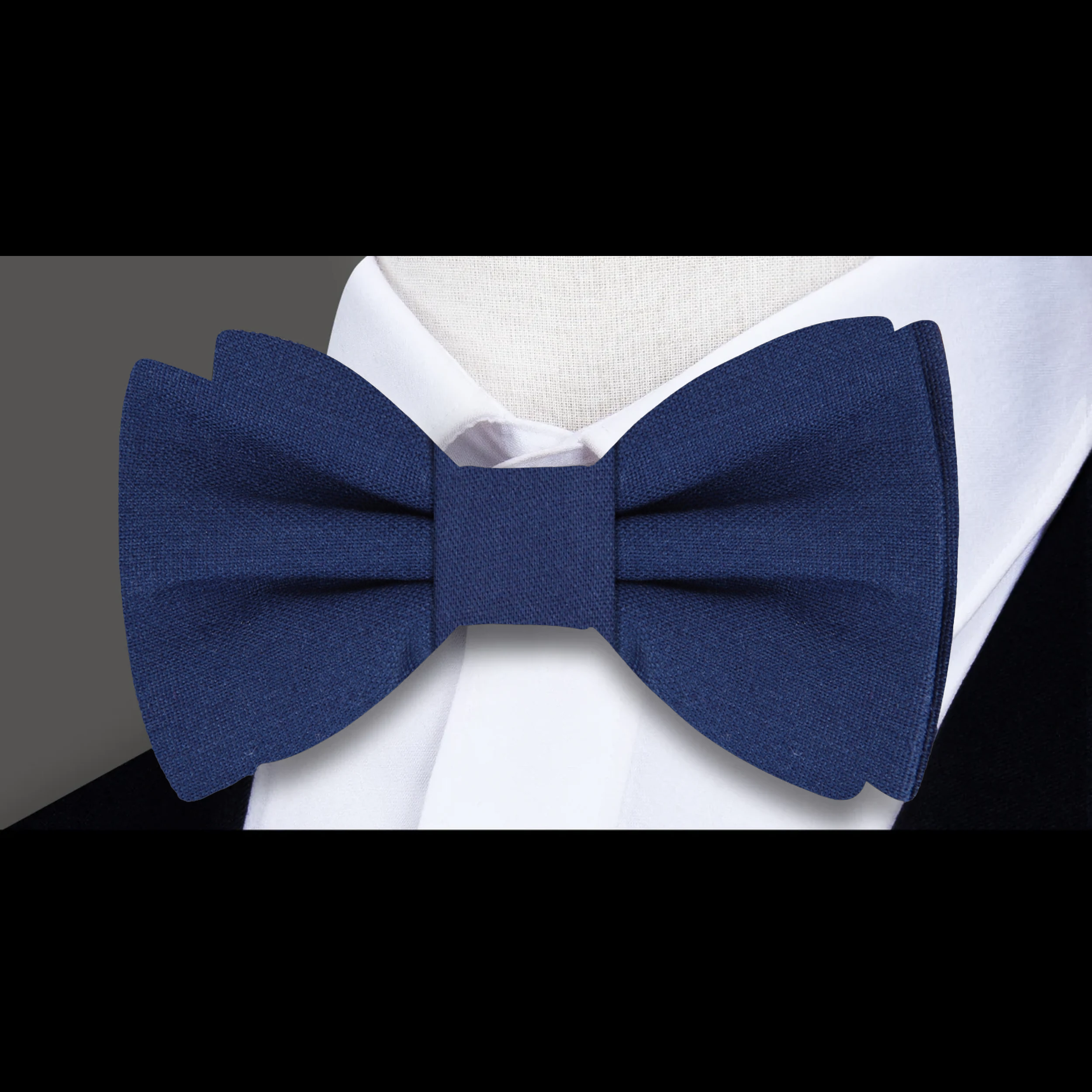 Groom wearing a navy linen bow tie with pocket square at a wedding reception