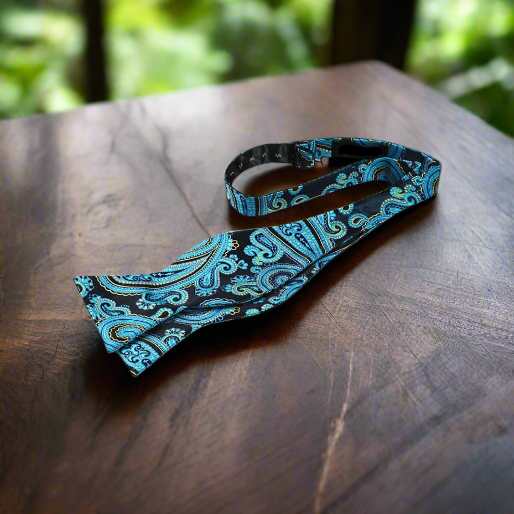 Elegant blue paisley self-tie bow tie displayed on a suit jacket