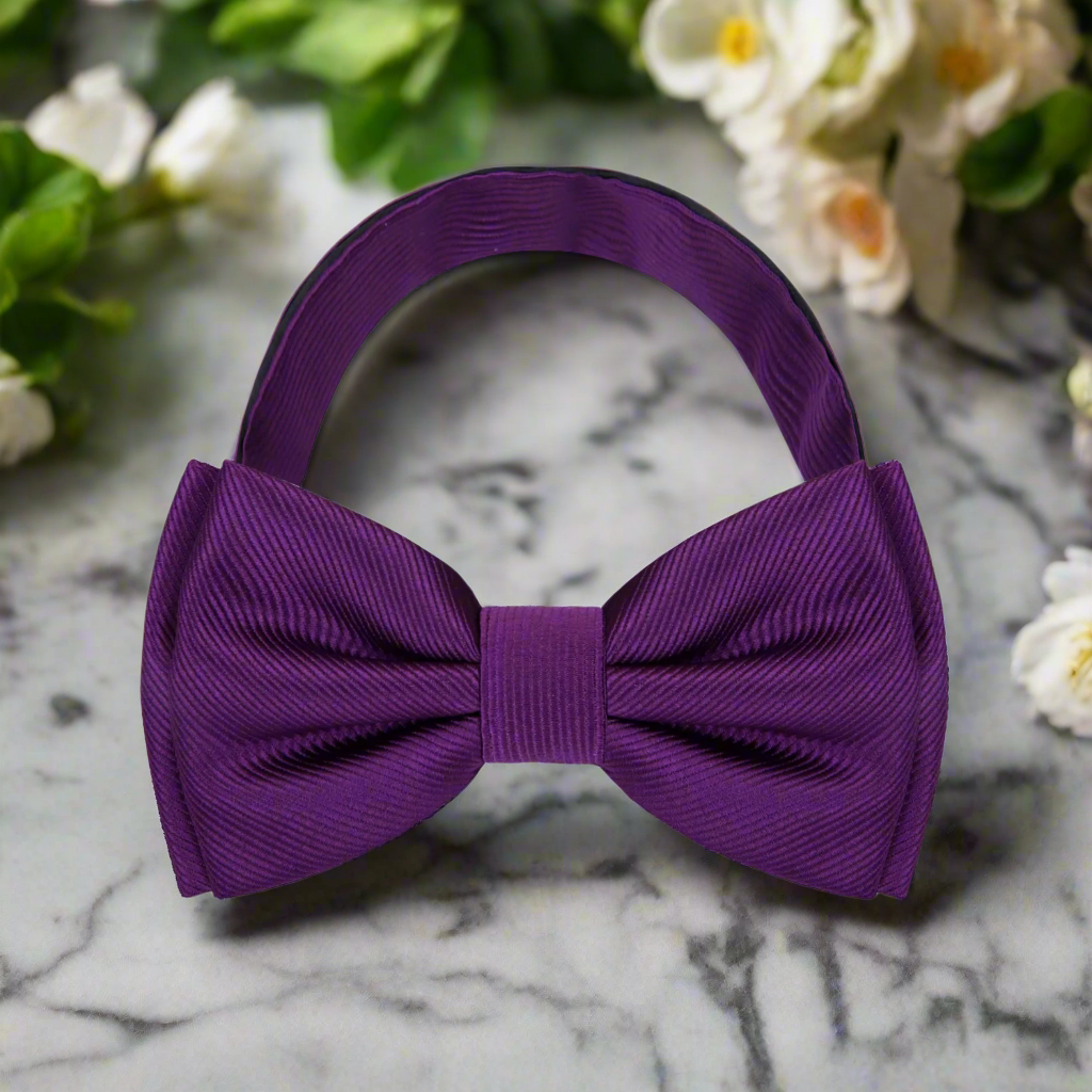 Elegant solid purple bow tie displayed on a classic white shirt, highlighting its rich color and texture.