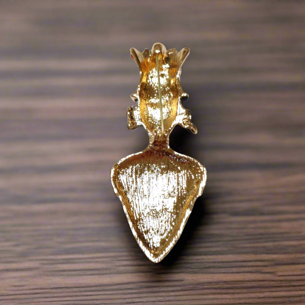 Close-up view of the Regal Pharaoh Kings Rhinestone Lapel Pin featuring gold, green, and black rhinestones.