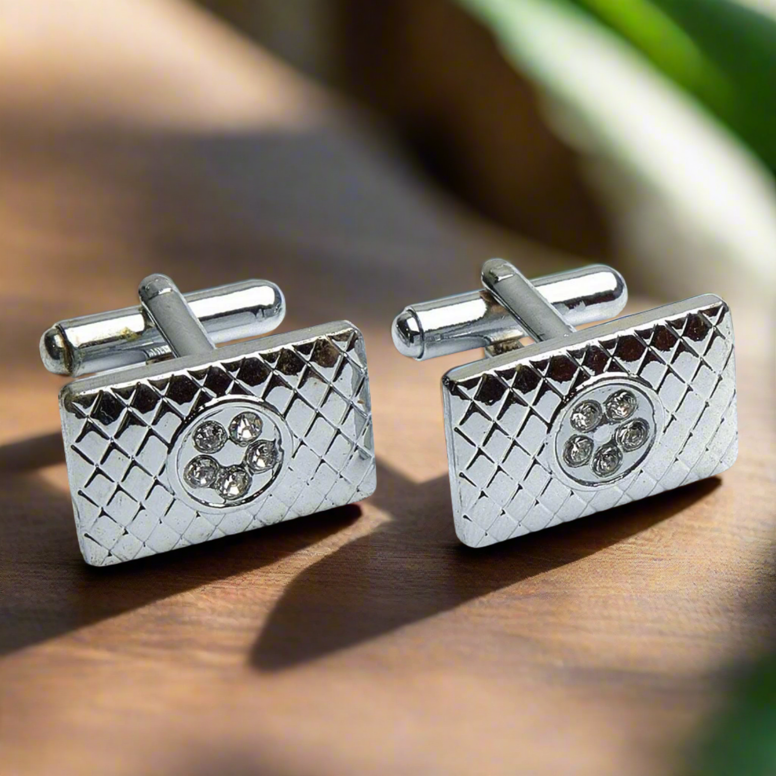 Close-up of chrome rectangular cufflinks showcasing embedded stones