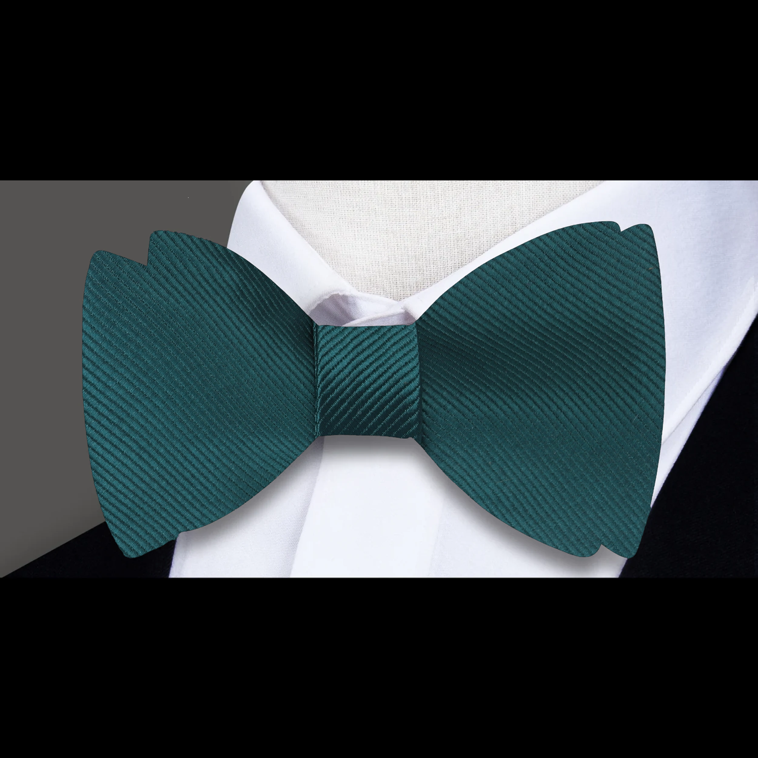 Close-up of a dark green silk bow tie with a subtle sheen, perfect for formal occasions