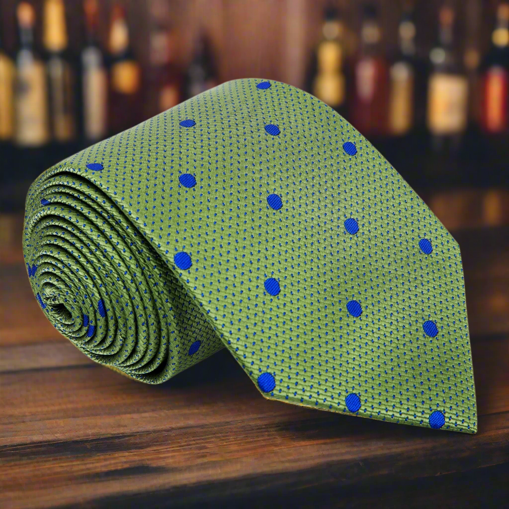 Detail view of the green and blue polka dot silk necktie draped on a hanger