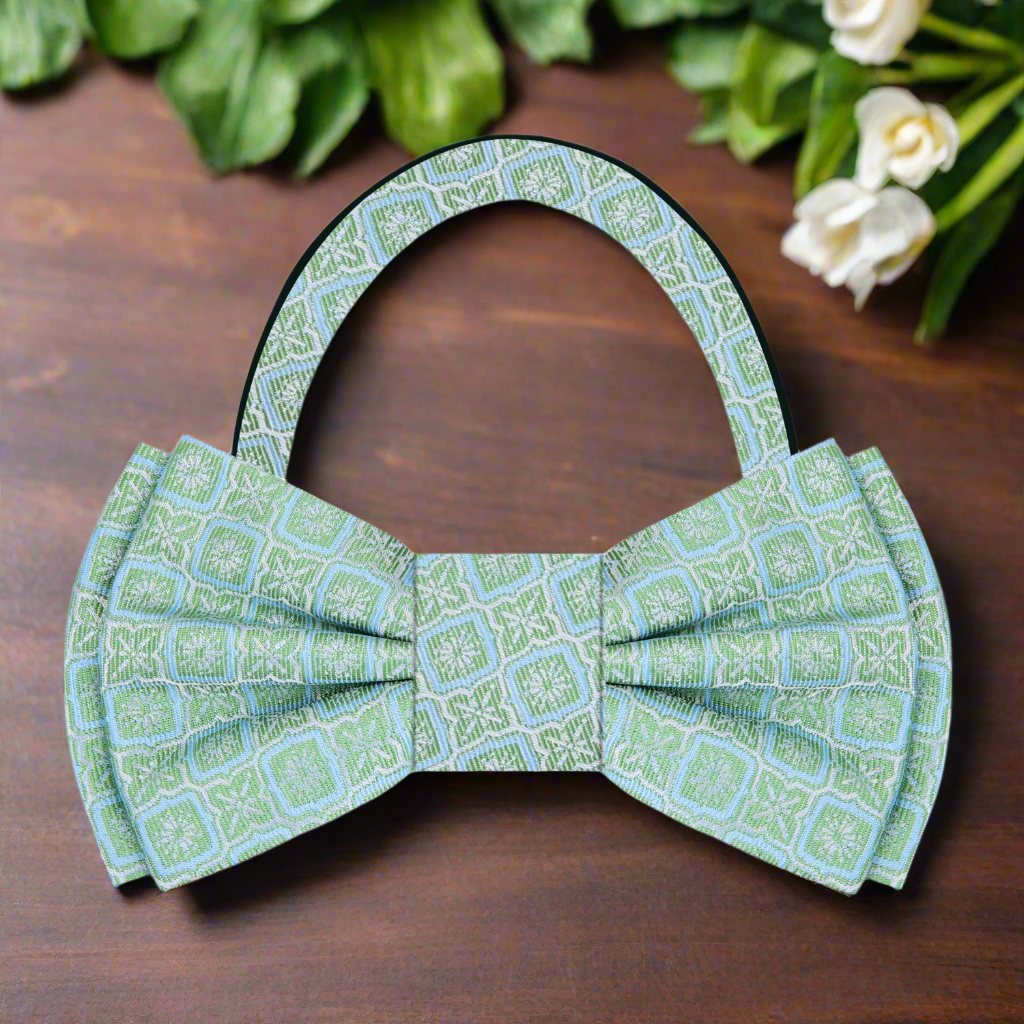 Flat lay of the vibrant geometric silk bow tie alongside a charcoal grey suit and a pocket square.