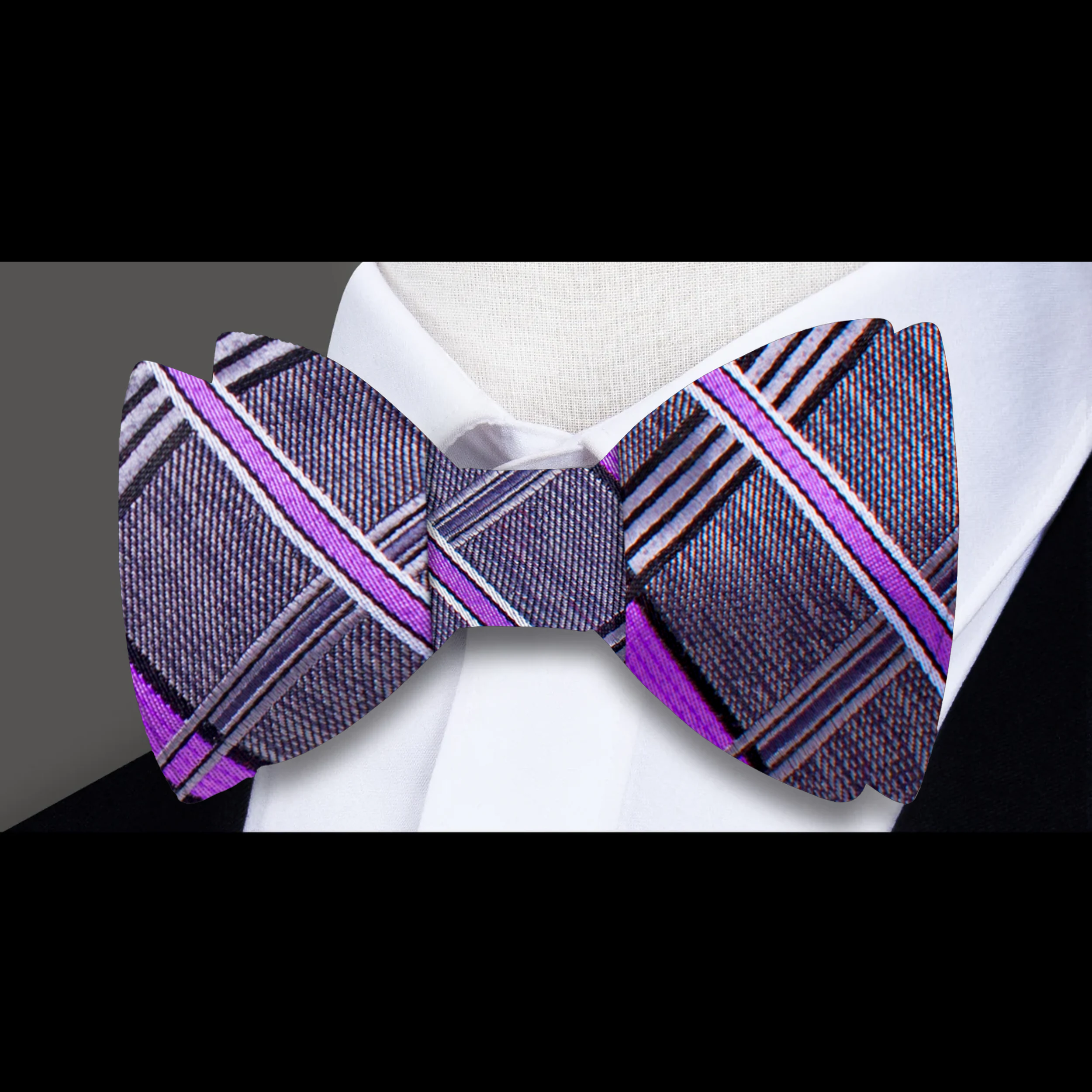 Close-up of the intricate plaid design of the silk bow tie against a light background.