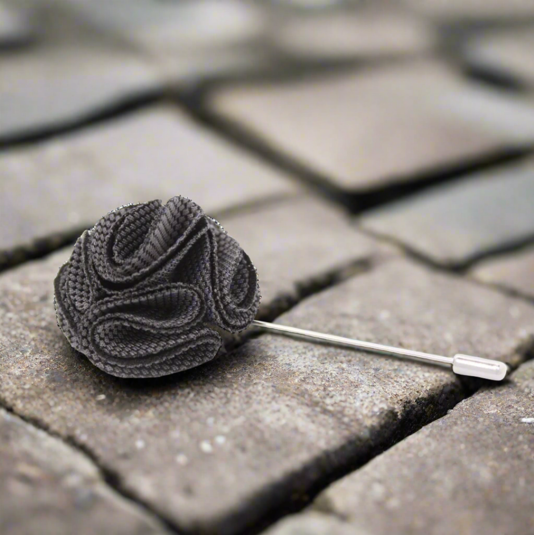 Close-up of the bright red Textured Burst Lapel Pin on a classic suit.